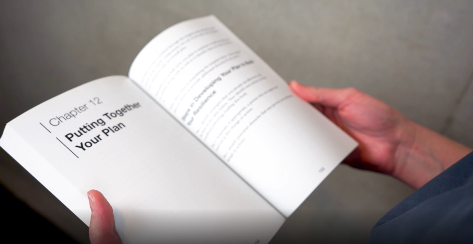 View of individual reading a book, on the left page contents include "Chapter 12 - Putting together your plan".